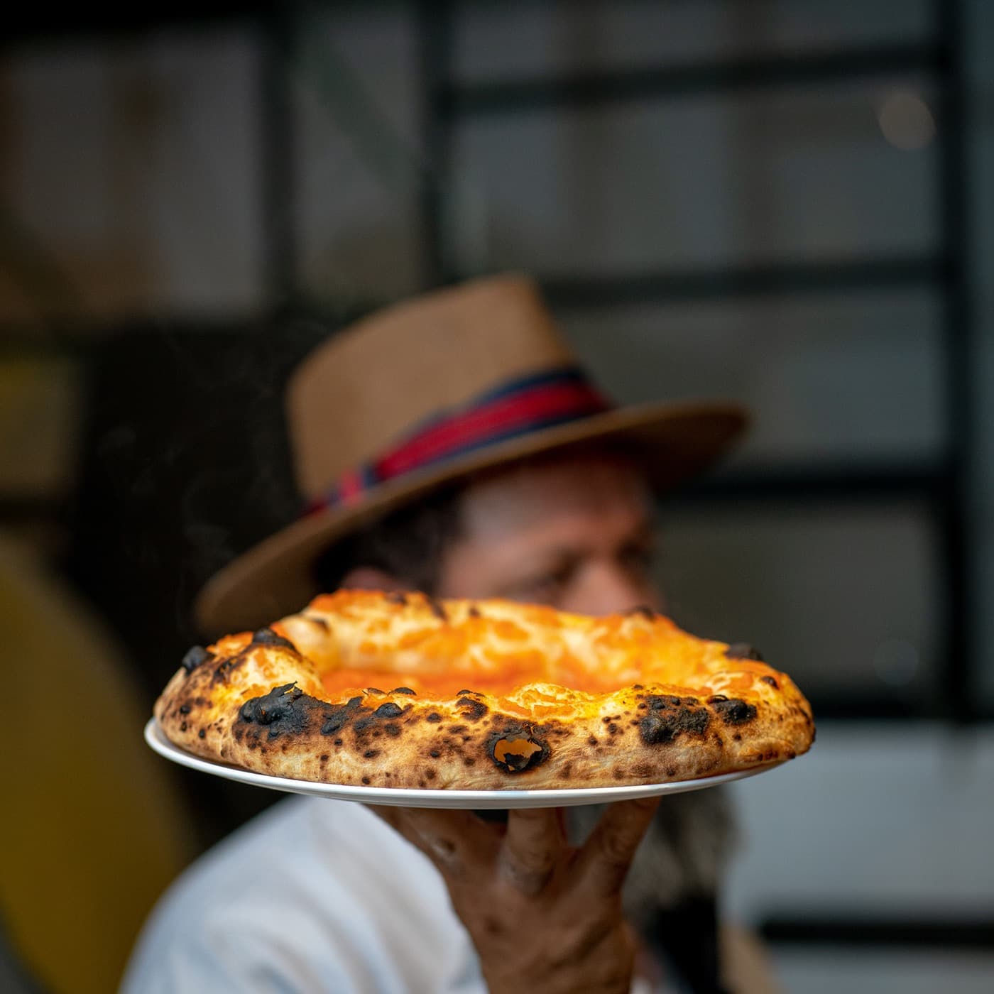 Alexandre Xavier de chapéu, segurando o prato com a pizza recém-saída do forno