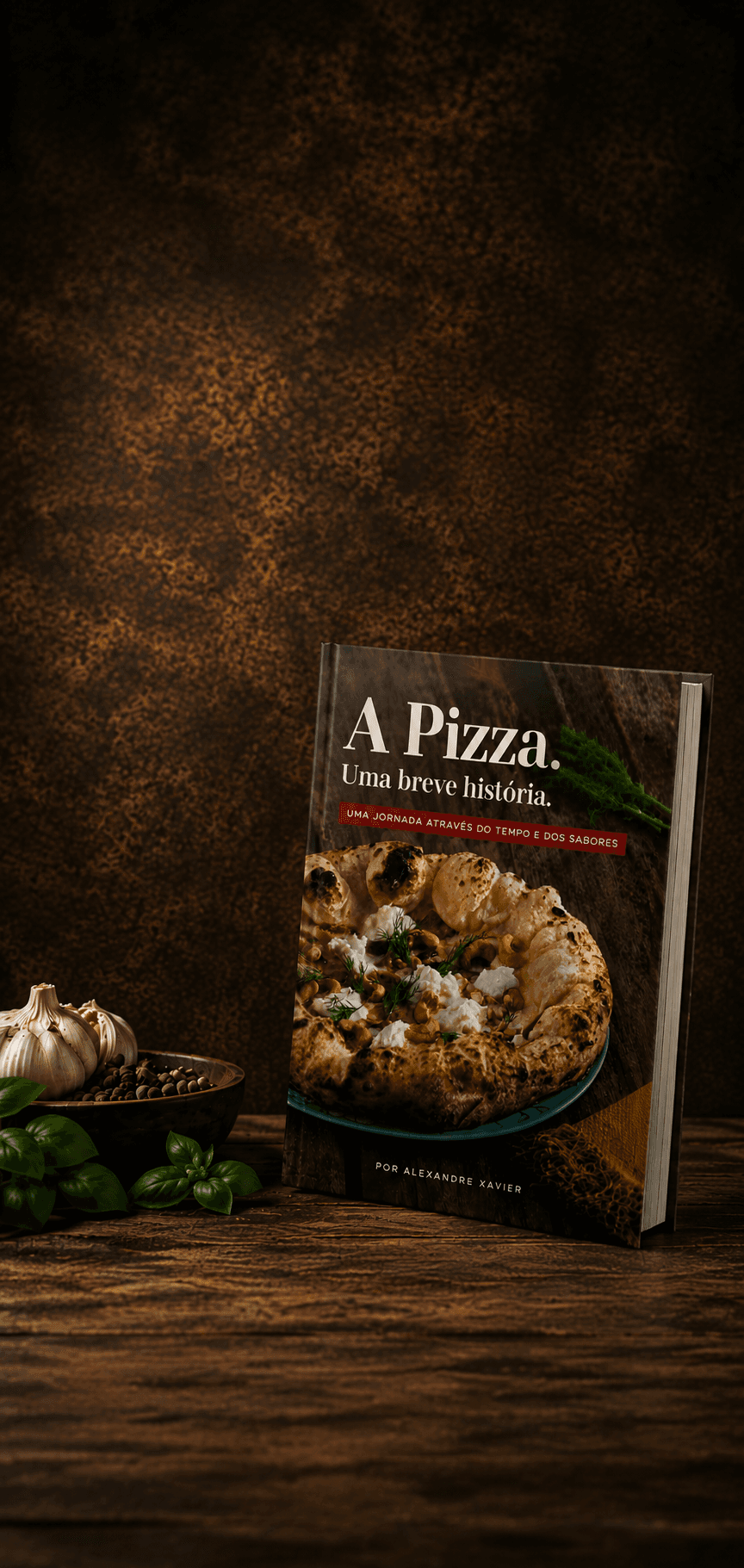 O livro A Pizza, Uma breve história, em pé na direita da bancada de madeira escura, com uma cabeça de alho, pimenta em uma tigela e folhas de manjericão no canto esquerdo